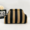 A beige and black striped knit cloud makeup bag resting on a white surface.