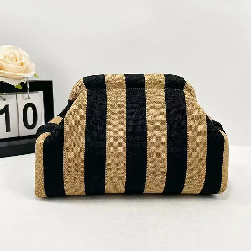 A beige and black striped knit cloud makeup bag resting on a white surface.