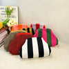 Collection de sacs à main en crochet rayés colorés pour la plage, exposés sur une surface blanche.
