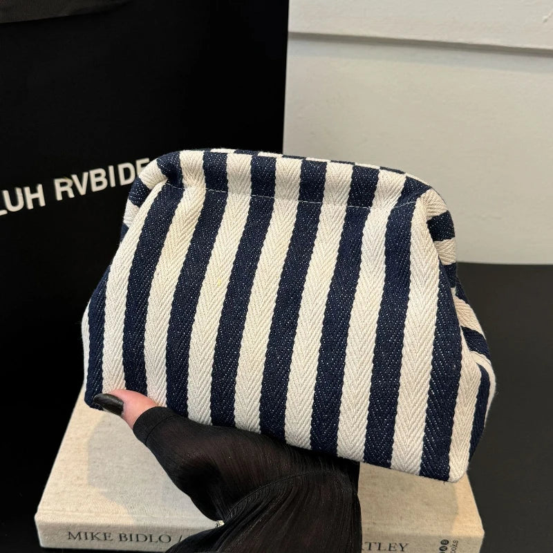 A striped cream and navy crochet handbag is displayed on a light surface.