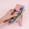 A hand holds a pink PU leather women's wallet with card holders and a coin pocket filled with cash.