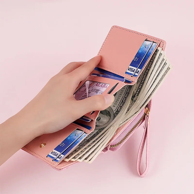 A hand holds a pink PU leather women's wallet with card holders and a coin pocket filled with cash.