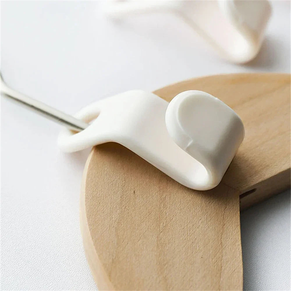 A white multi-hook wardrobe organizer is shown resting on a light wooden surface.