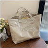 A beige transparent waterproof PVC tote bag is displayed on a wooden surface next to some flowers.