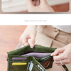 A close-up of a dark olive green foldable wallet with a gold zipper detail being held by a hand.