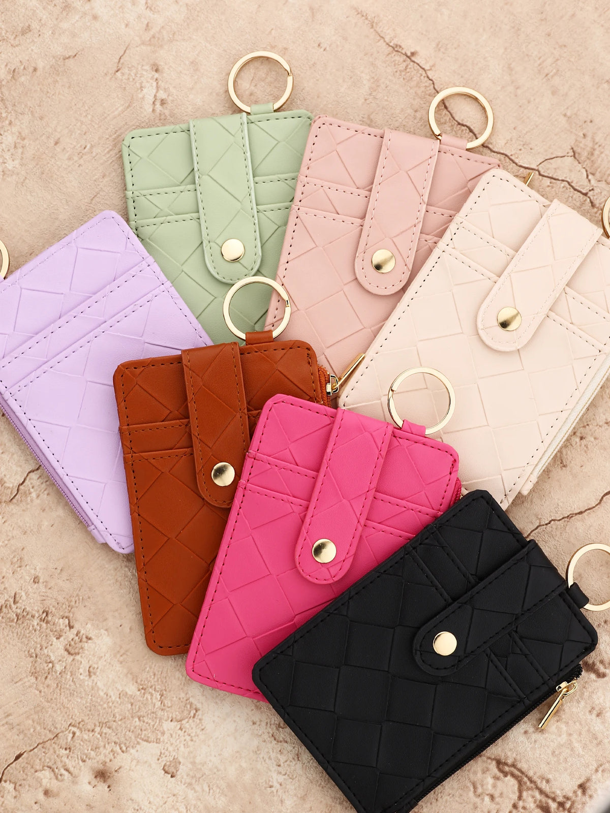 A collection of pastel pink, green, purple, and orange PU leather card holder wallets with gold rings.