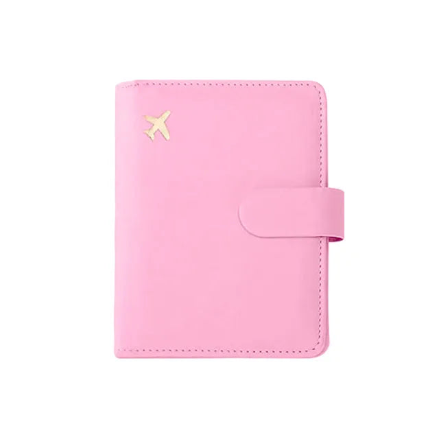 A pink leather passport organizer with a flap closure and an embossed airplane symbol.
