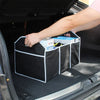 A hand places a box into a black multi-pocket car trunk organizer inside a vehicle's trunk.