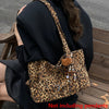 A person is holding a leopard print casual tote bag with brown leather accents and a black coat.