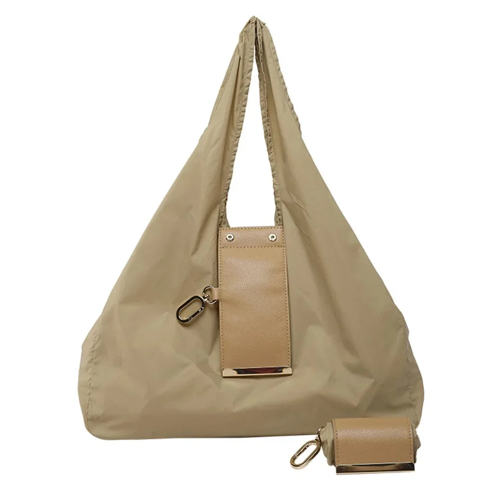 A beige foldable mini keychain tote bag with a flap closure and leather accents.