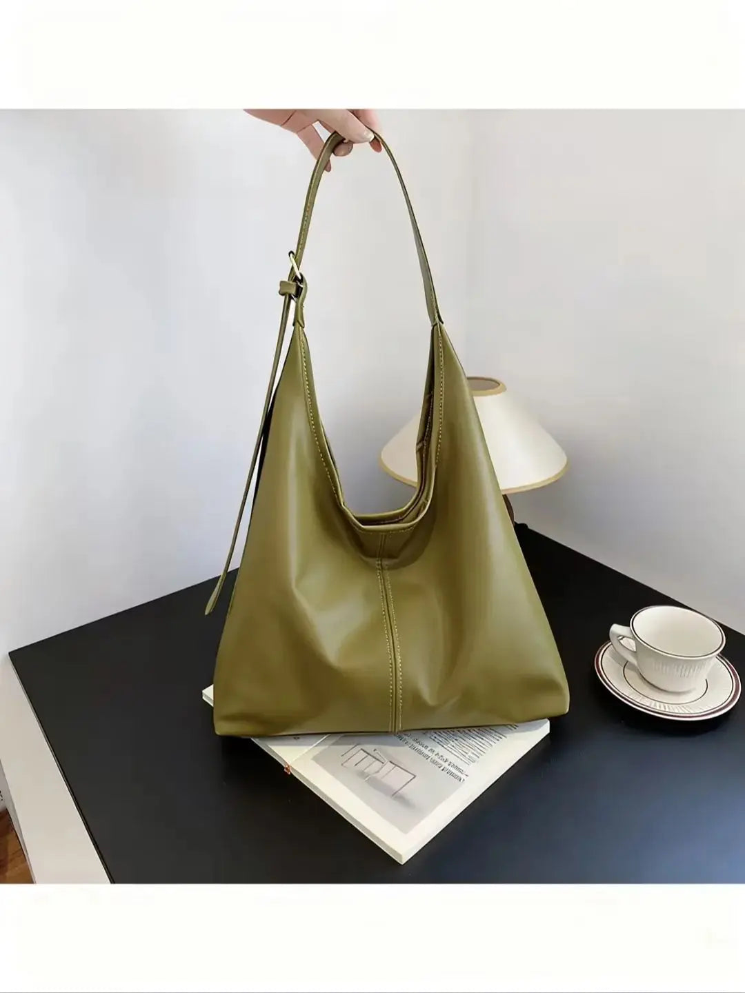 Ein hellolivgrüner Retro-Canvas-Totebeutel auf einem dunklen Tisch neben einer weißen Tasse und Untertasse.