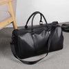 Bolsa de viaje retro negra de cuero PU sobre una alfombra gris.