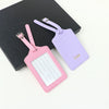 A set of two custom PU leather luggage tags, one pink and one purple, with a cross-pattern detail.