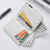 A white slim faux leather business card wallet with several cards and a black pen lying on a white surface.