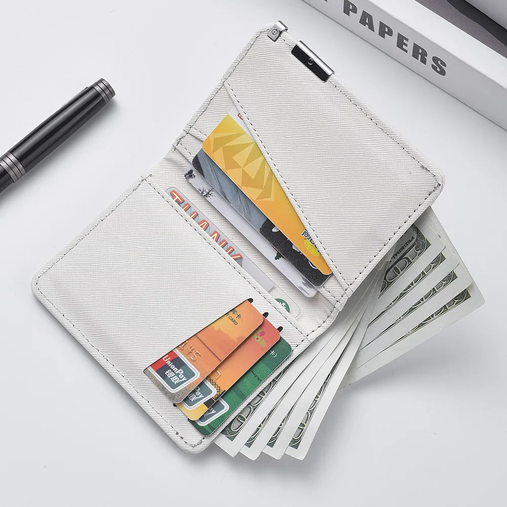 A white slim faux leather business card wallet with several cards and a black pen lying on a white surface.