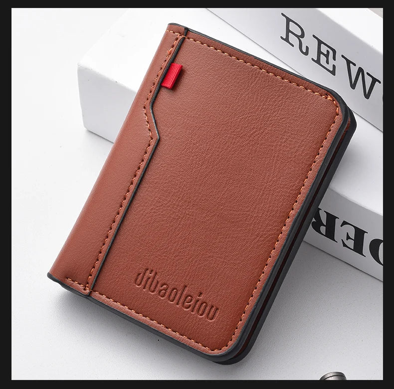 A brown leather credit card wallet with stitching and a red pull tab resting on a white surface.