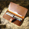 A brown genuine leather long bi-fold wallet with a snap closure resting on an old map.