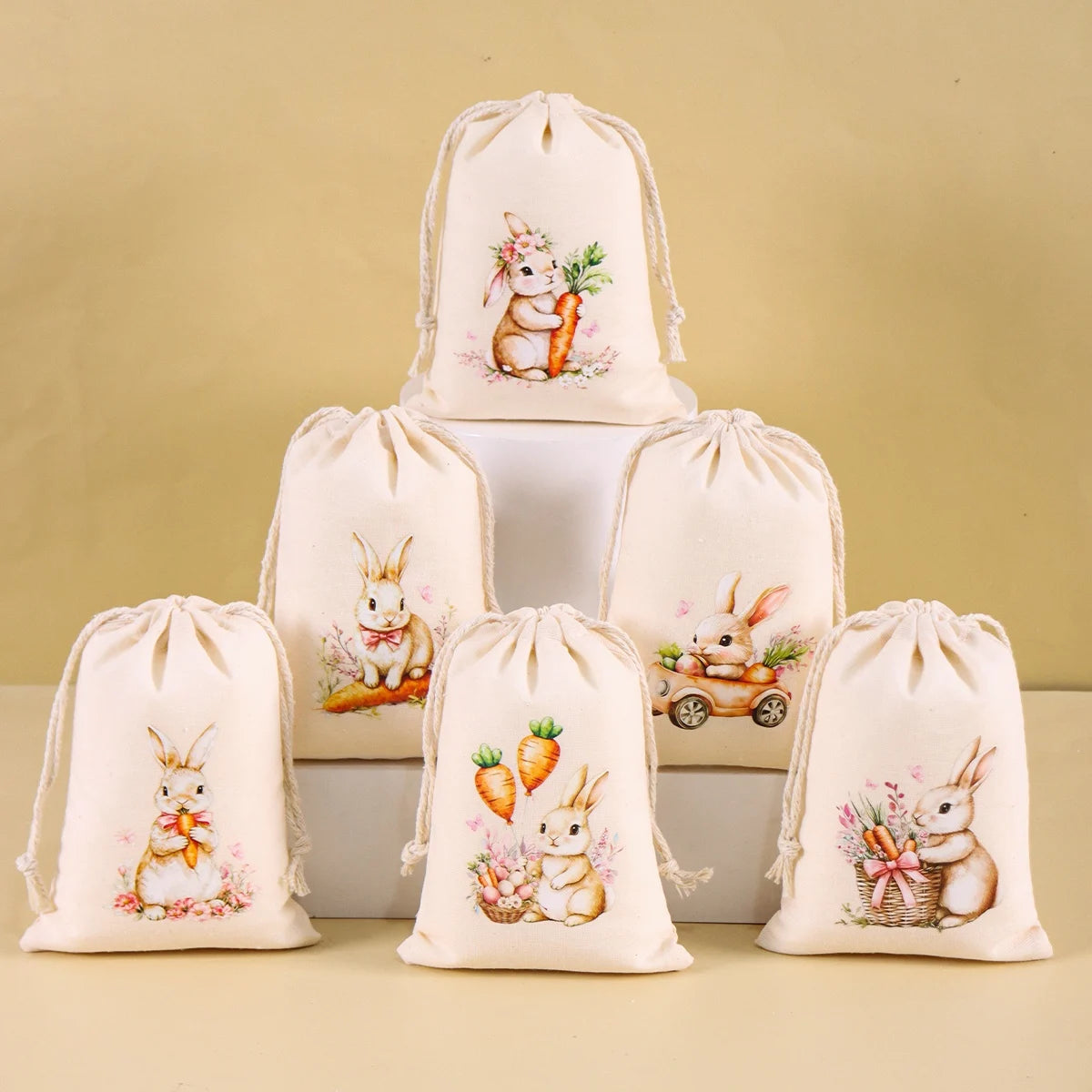 A set of six beige drawstring gift bags featuring illustrations of Easter bunnies and carrots.