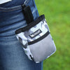 A black and white camouflage pet training treat pouch is shown attached to a pair of blue jeans.