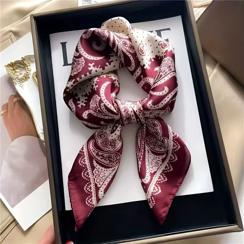 A deep burgundy paisley silk scarf tied in a bow displayed in a black frame.