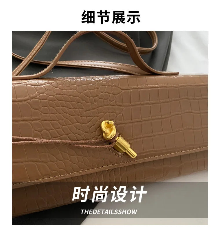 Close-up detail shot of a brown crocodile-embossed PU leather clutch bag showing the gold hardware and stitching.