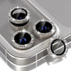 A silver camera lens protector with a glitter diamond lens and metal frame resting on a surface.