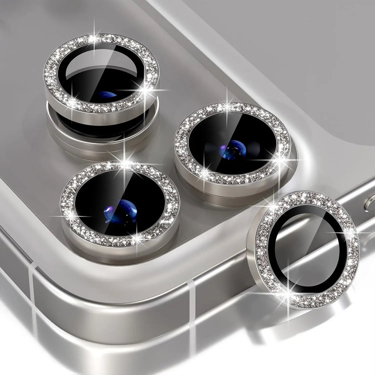 A silver camera lens protector with a glitter diamond lens and metal frame resting on a surface.