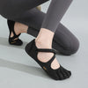 A pair of black women's barefoot five-toe shoes with an adjustable strap shown on a person's foot.