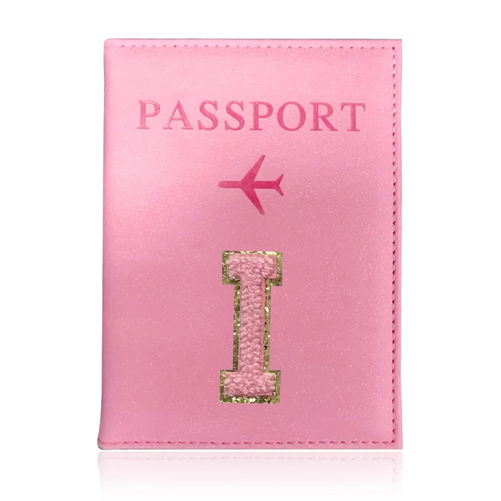 A pink leather passport holder with the word PASSPORT and a gold initial I embossed on it.