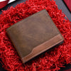 A brown PU leather men's wallet with an ID card holder resting on a vibrant red shredded fabric.