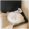 A white PU leather crossbody saddle bag with a chain strap is displayed inside a black box.