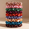 A stack of 19 thin scrunchies hair ties in various shades of pink, green, purple, and orange.