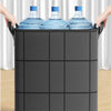 Hands are placing bottled water into a large black non-woven storage bag.