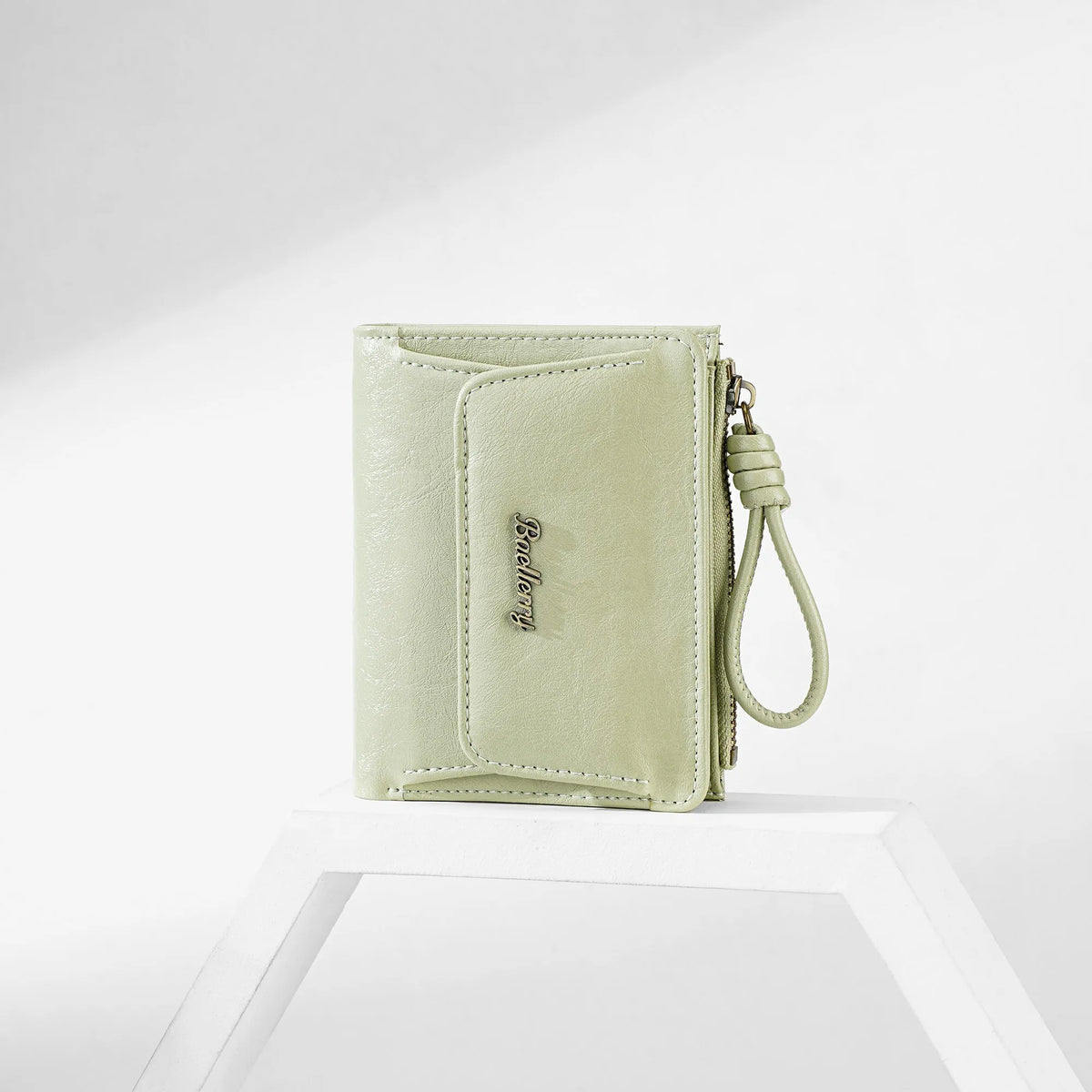 A light green PU leather mini wallet with a stitched detail and a leather strap is displayed on a white surface.