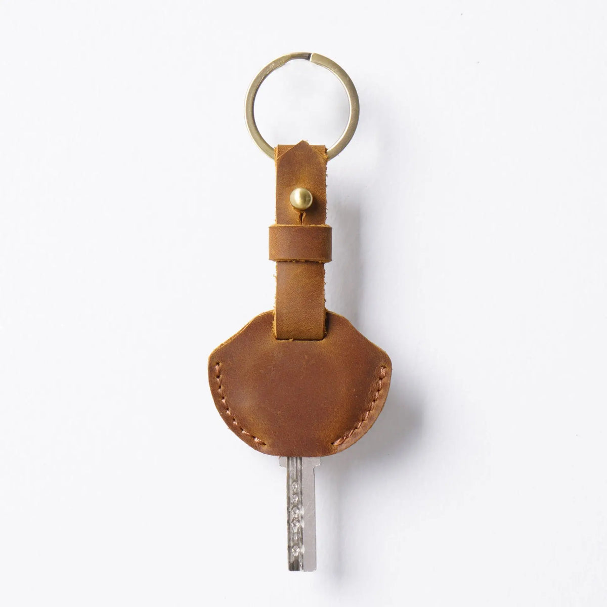 A brown genuine leather key fob cover with a metal keychain ring and attached to a leather strap.