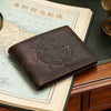 A dark brown leather wallet featuring an engraved compass design resting on old maps and a wooden surface.