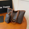 A brown geometric patterned tote bag with leather trim resting on a wooden surface.