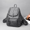 A gray vintage soft leather backpack with zippered pockets is shown against a light gray background.