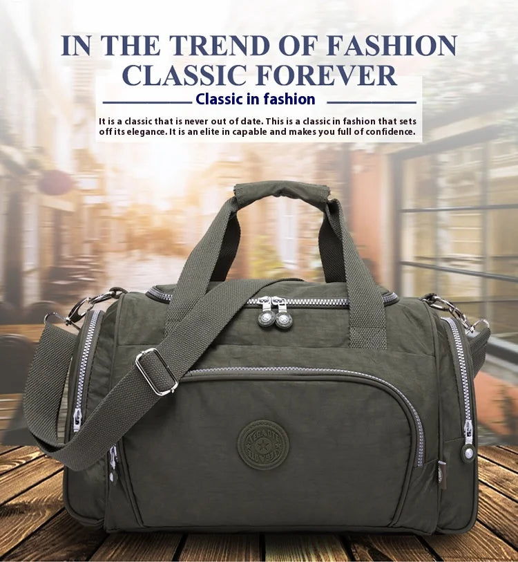 A dark olive green durable nylon travel duffle bag with a padded shoulder strap is shown on a wooden surface.