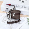 A dark brown leather coin purse with a silver chain and lanyard is displayed on a white background next to a book.