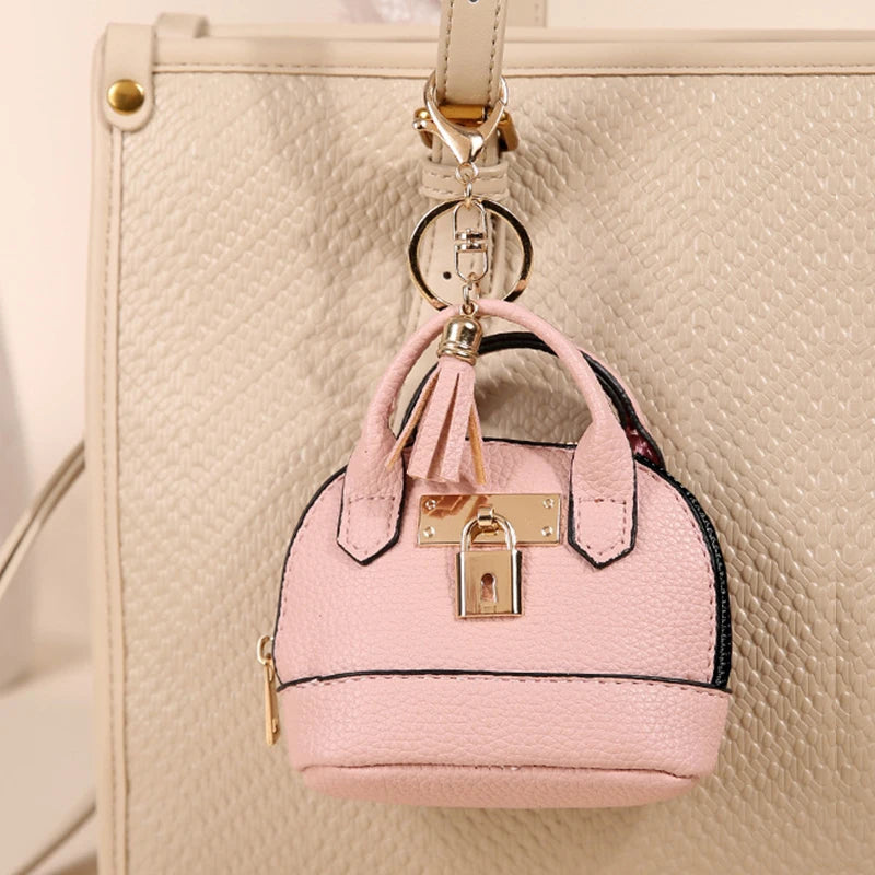 Portefeuille en plastique rose luxueux avec clé, suspendu à une sangle en cuir sur fond beige texturé.