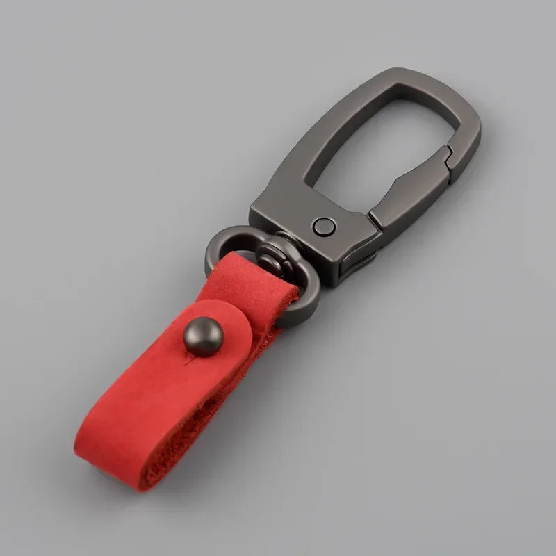 A genuine leather keyring keychain with a dark gray clasp and a red fabric strap.