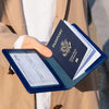A hand holds a navy blue passport holder wallet with a US passport inside, against a light beige jacket.
