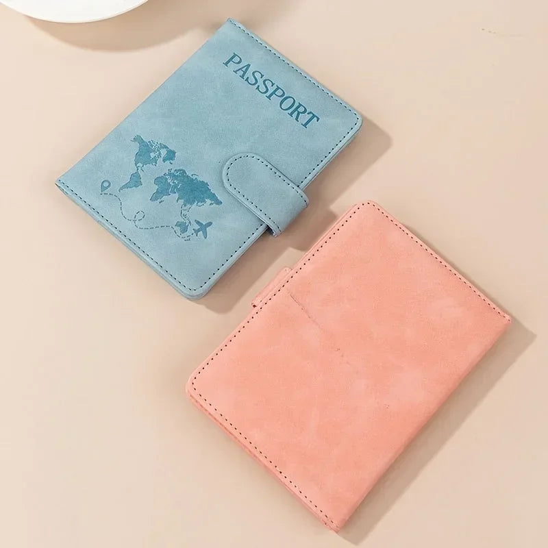 A light blue passport wallet with a map design and a peach-colored leather wallet are displayed on a beige background.