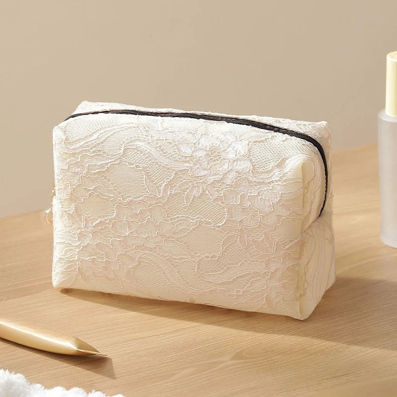 A rectangular cream-colored lace mesh organizer bag resting on a wooden surface with a gold applicator visible.