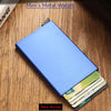 Cartera delgada de metal azul abierta, mostrando tarjetas de crédito y una identificación, sobre una superficie de madera.