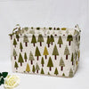 A beige fabric storage basket with handles featuring a repeating pattern of green and brown pine trees.