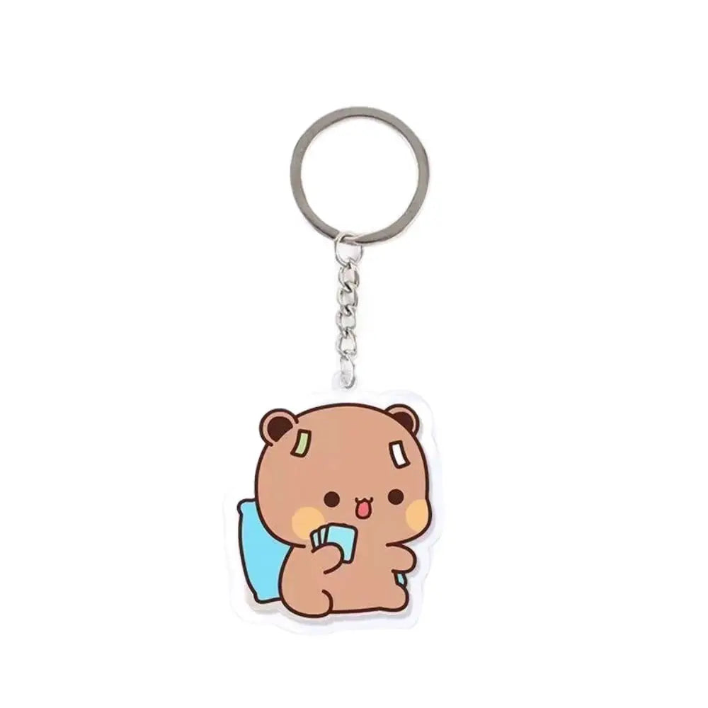 A cute brown cartoon bear charm with a small blue accessory attached to a silver keyring.
