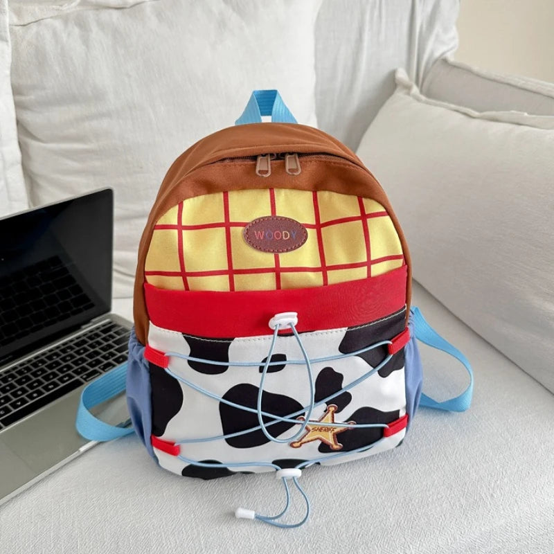A brown and yellow cow print fashion backpack with blue straps resting on a white surface.