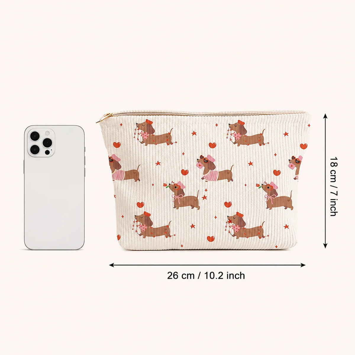 A beige cosmetic bag with a pattern of pink and brown dachshunds and hearts, shown next to an iPhone for scale.